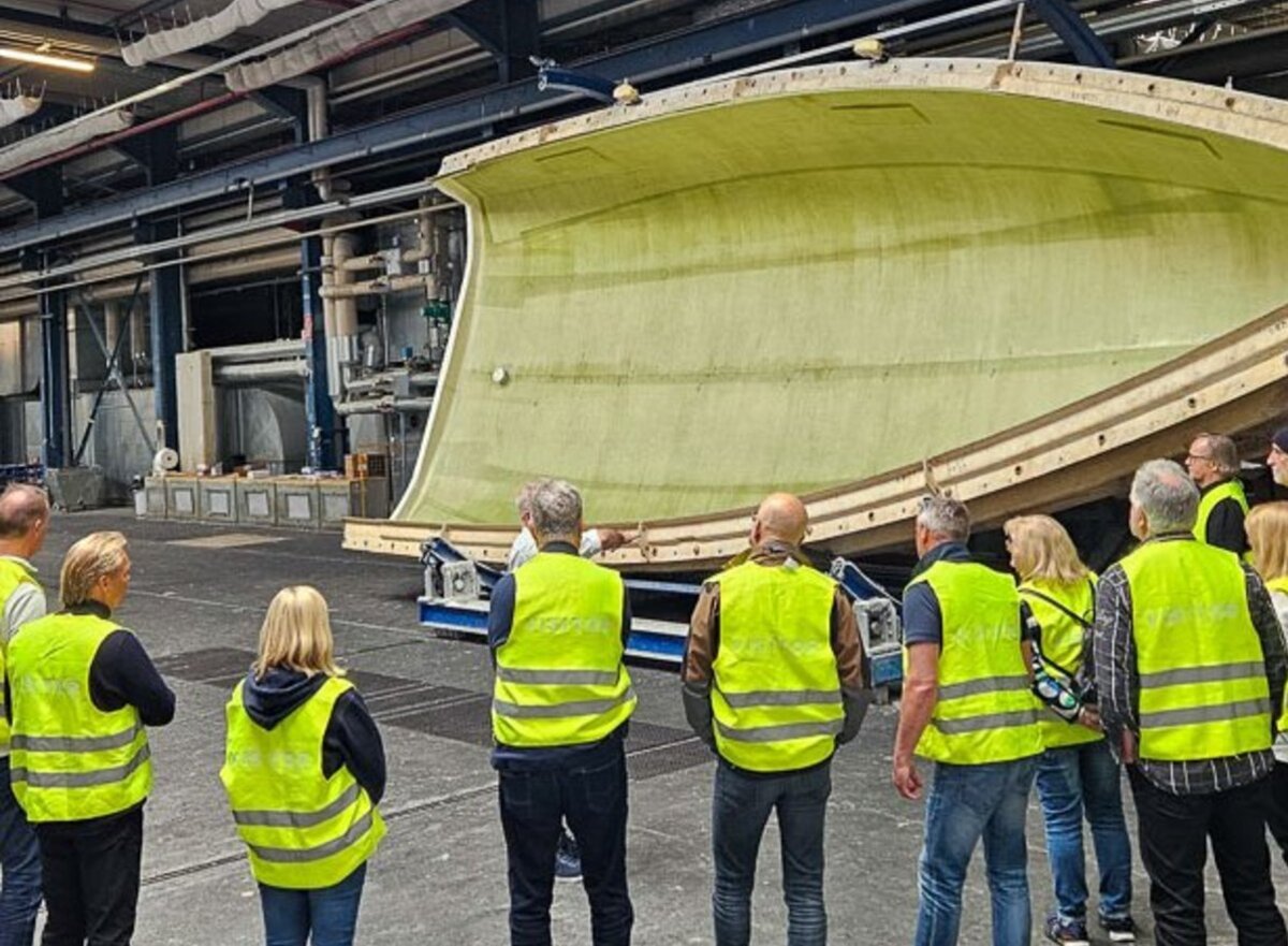 Menschen vor einer Rumpfschale einer Segelyacht